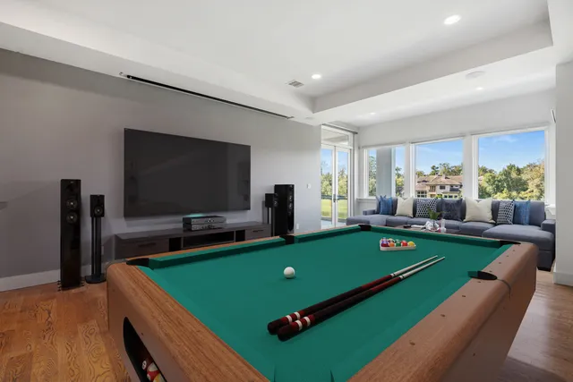 a bedroom with a large bed a couch and potted plant with wooden floor