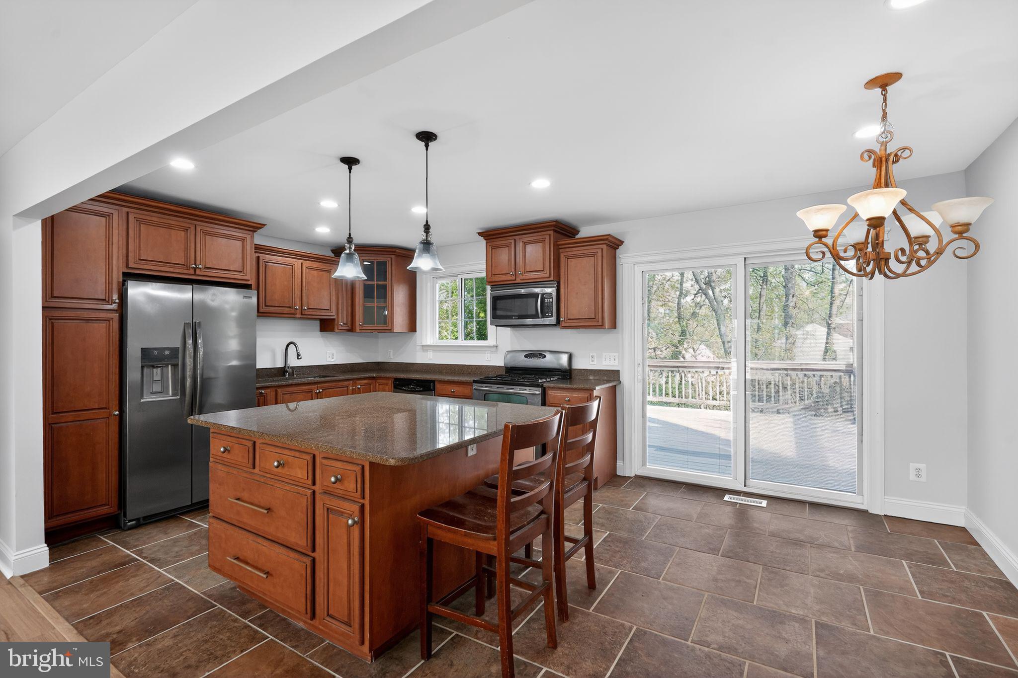 73 Greenvale Road Cherry Hill, NJ 08034 - Photo 3 of 23 a kitchen with stainless steel appliances granite countertop a sink a stove a refrigerator a microwave a dining table and chairs with wooden floor