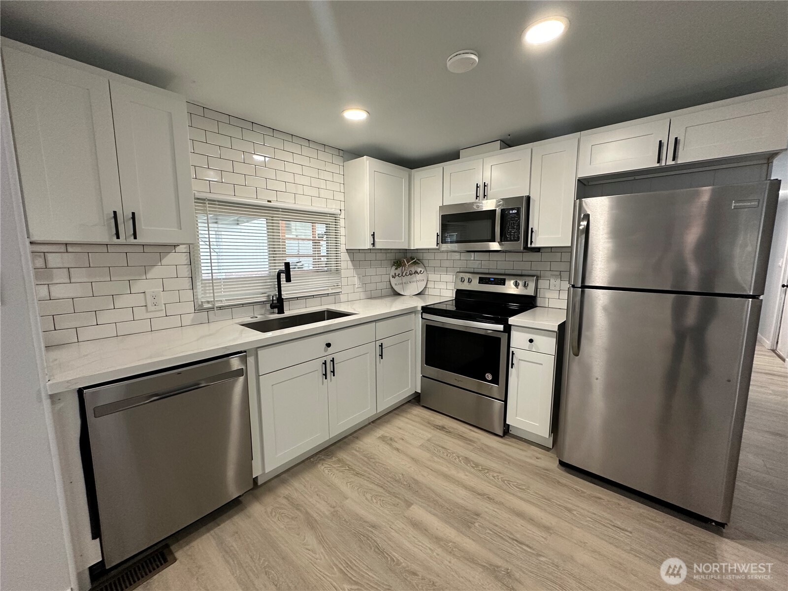 a kitchen with a refrigerator a sink dishwasher a stove and white cabinets with wooden floor