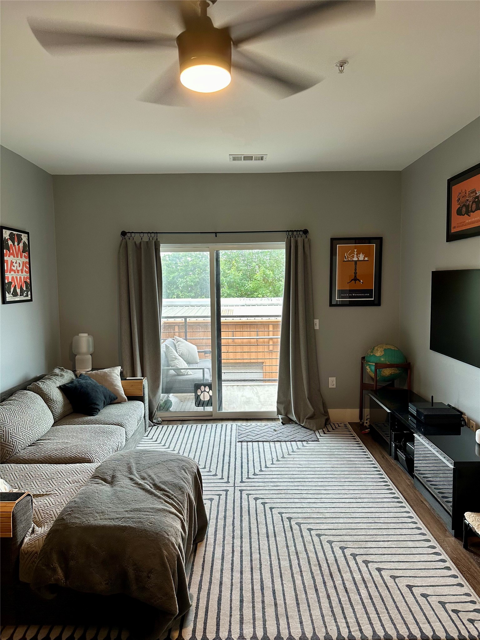 6444 Burnet Road, Unit 203 Austin, TX 78757 - Photo 11 of 30 The living area features a ceiling fan, sliding glass doors to a balcony, and a wood-look floor