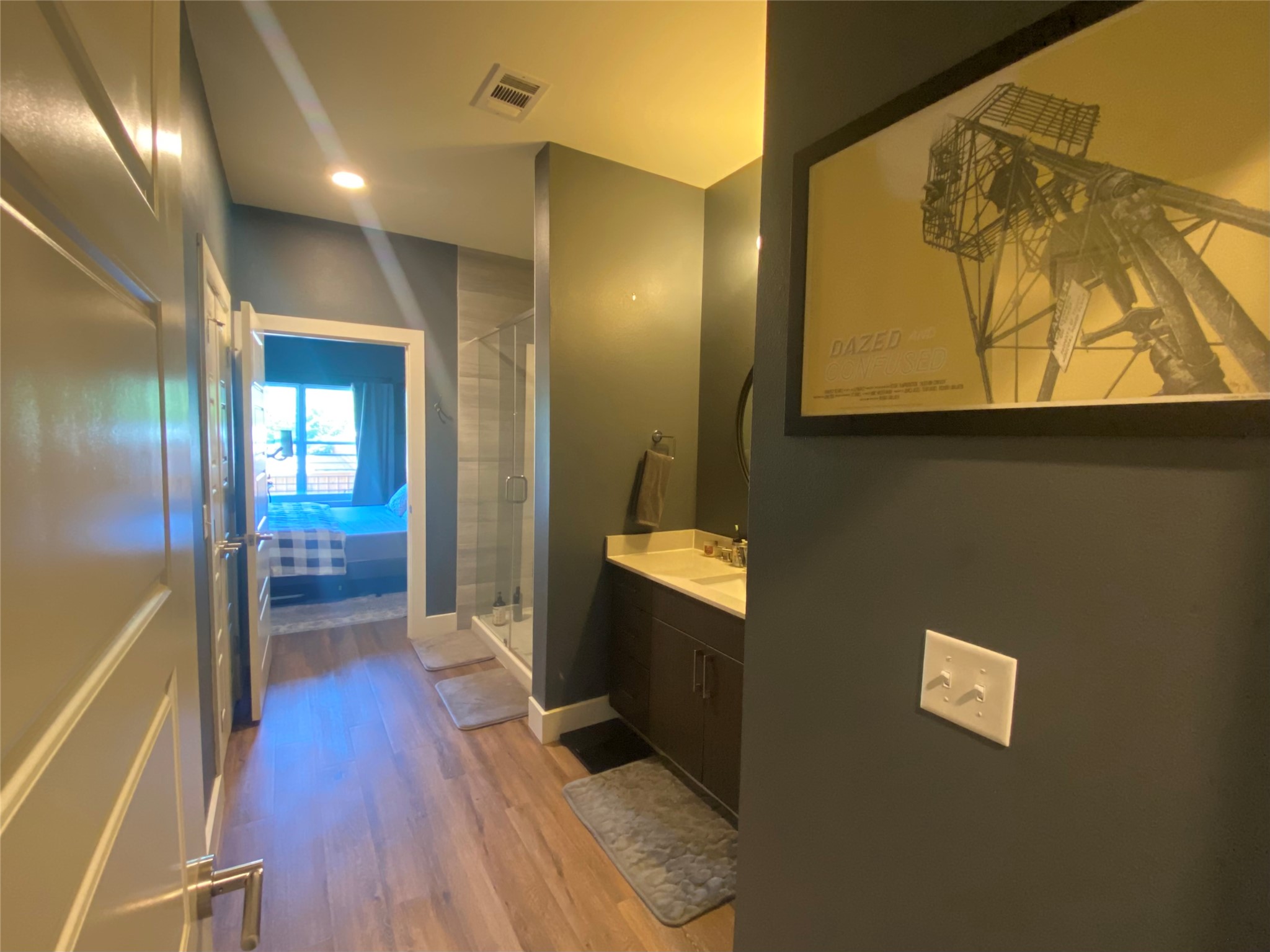 6444 Burnet Road, Unit 203 Austin, TX 78757 - Photo 17 of 30 The property features a bathroom with a shower enclosure, a vanity with a sink, and a hallway with wood flooring