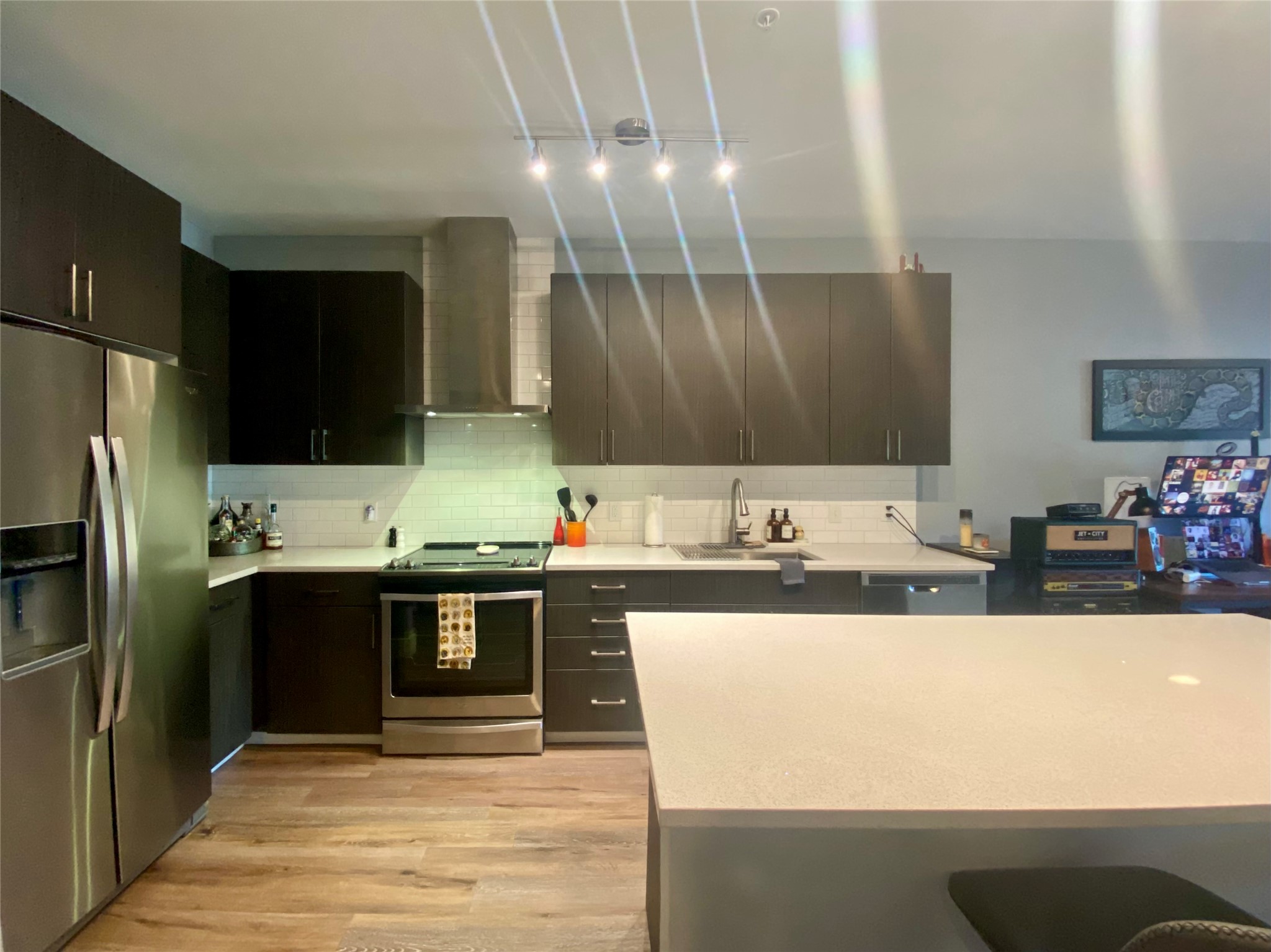 6444 Burnet Road, Unit 203 Austin, TX 78757 - Photo 23 of 30 Contemporary kitchen featuring dark cabinetry, stainless steel appliances, a white tile backsplash, and a light-colored countertop
