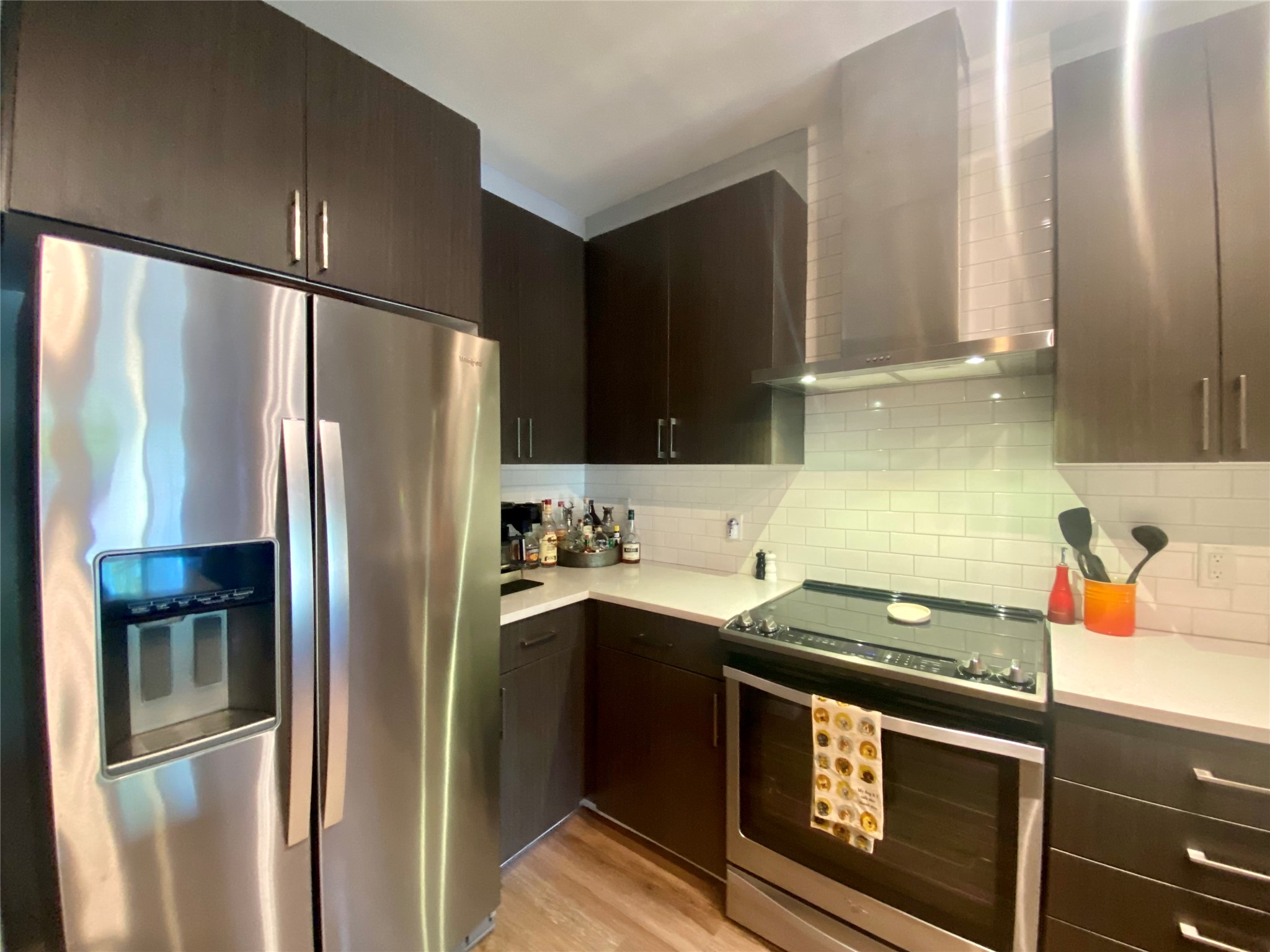 6444 Burnet Road, Unit 203 Austin, TX 78757 - Photo 24 of 30 The property features a kitchen with dark cabinetry, stainless steel appliances, white countertops, and a white subway tile backsplash