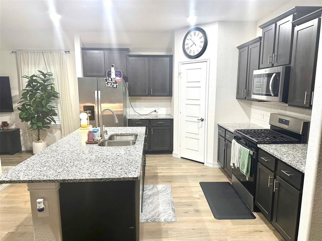 324 Revolution Road Fate, TX 75189 - Photo 4 of 15 Contemporary kitchen featuring an island with a double basin sink and granite countertops