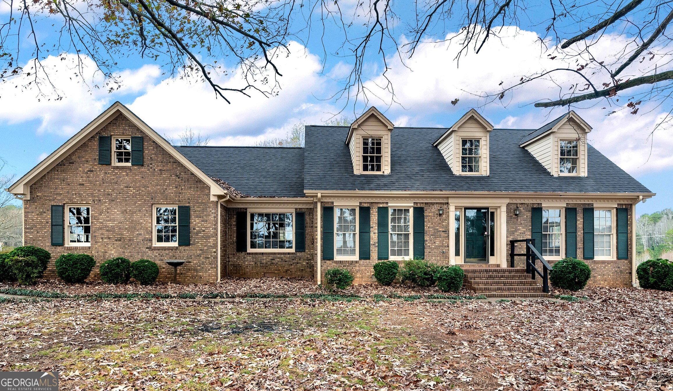 a view of a brick house with large windows and a small yard
