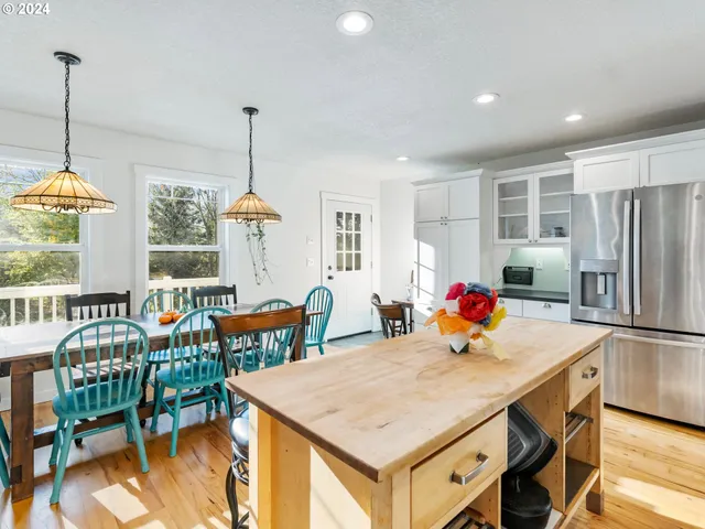 a kitchen with stainless steel appliances granite countertop a table chairs and a refrigerator