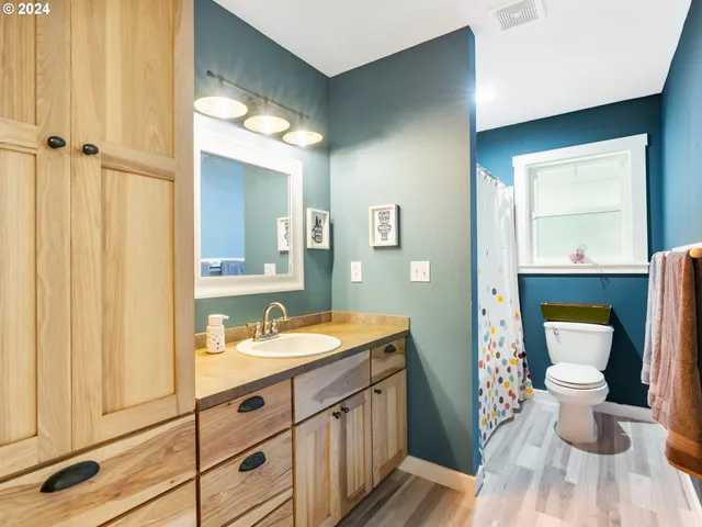 a spacious bathroom with a sink a toilet a mirror and shower