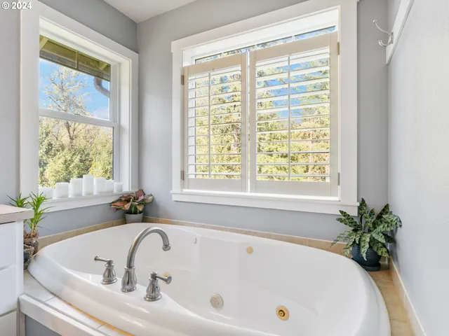 a white bath tub sitting in a bathroom next to a window