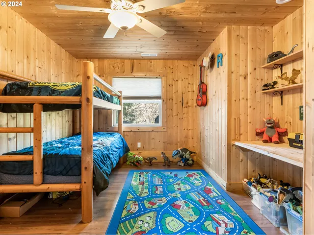 a bedroom with a bed a dresser and wooden floor