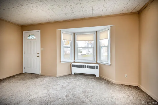 an empty room with a exposed radiator down to a window