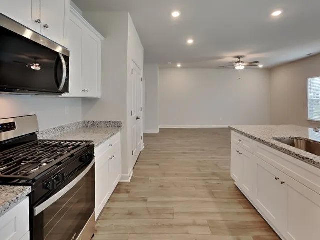 a kitchen with stainless steel appliances granite countertop a stove a sink and a microwave