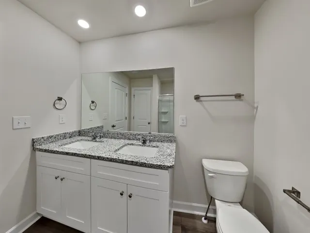 a bathroom with a granite countertop sink a toilet and a mirror