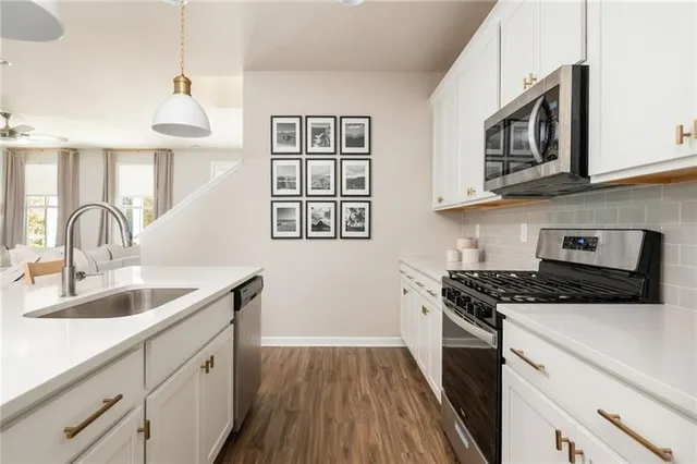a living room with stainless steel appliances furniture a fireplace a flat screen tv and a kitchen view