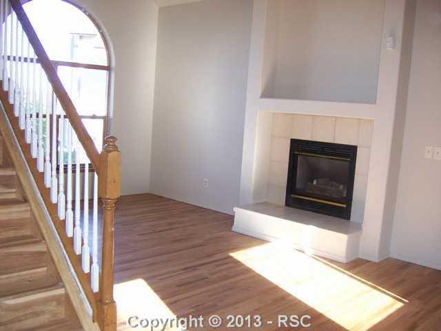 609 Rye Ridge Road Fountain, CO 80817 - Photo 3 of 12 Living room with vaulted ceiling, hardwood floor, ceiling fan, gas log fireplace & built-in entertainment center.