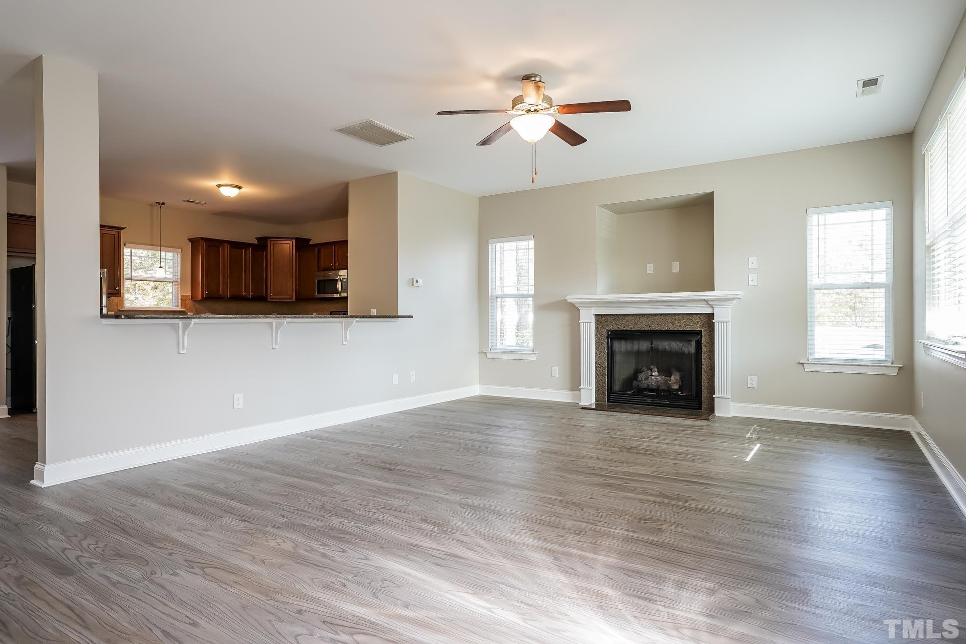 49 Burrage Drive Angier, NC 27501 - Photo 4 of 17 a view of a livingroom with a fireplace a ceiling fan and windows