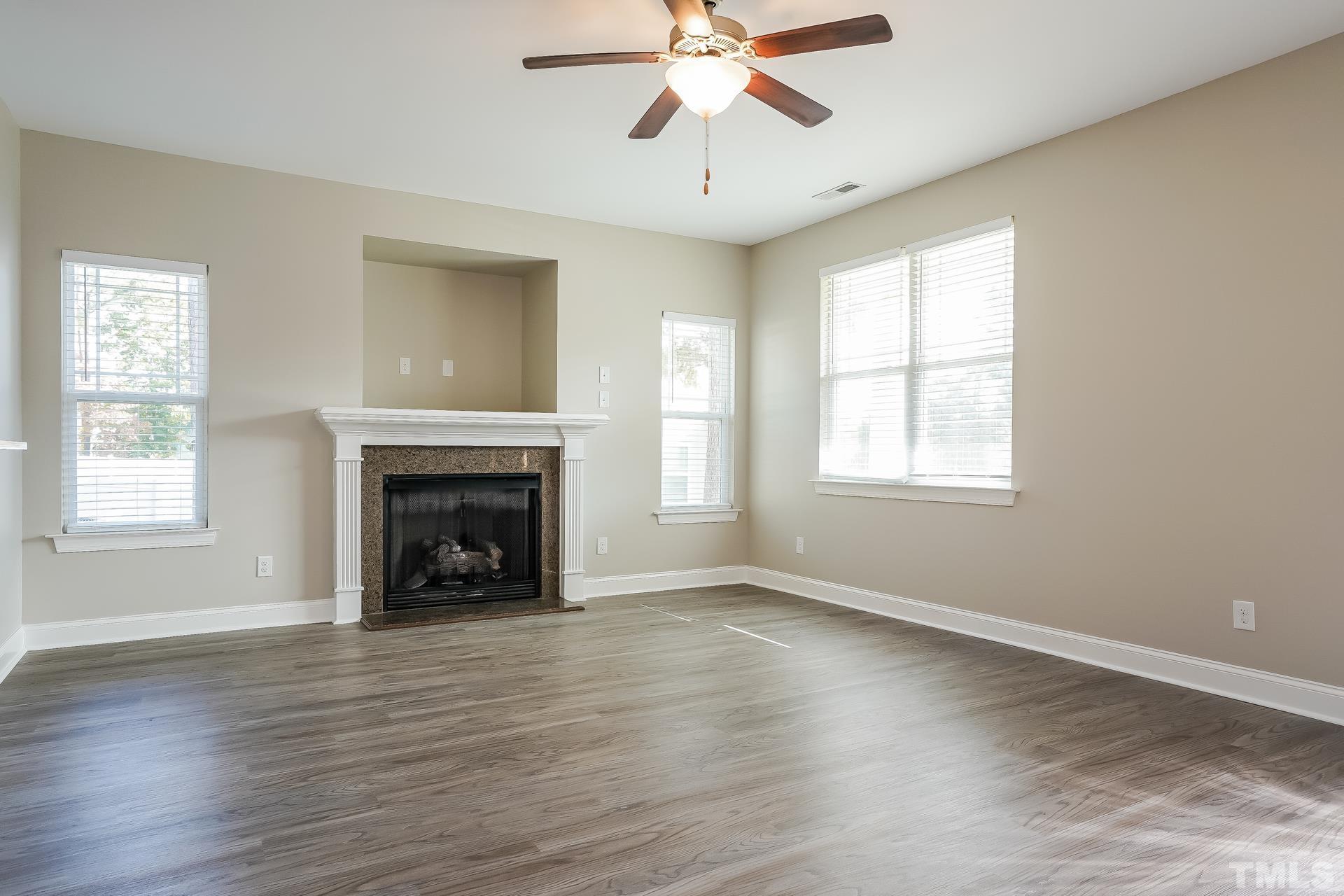 49 Burrage Drive Angier, NC 27501 - Photo 5 of 17 an empty room with windows fireplace and wooden floor