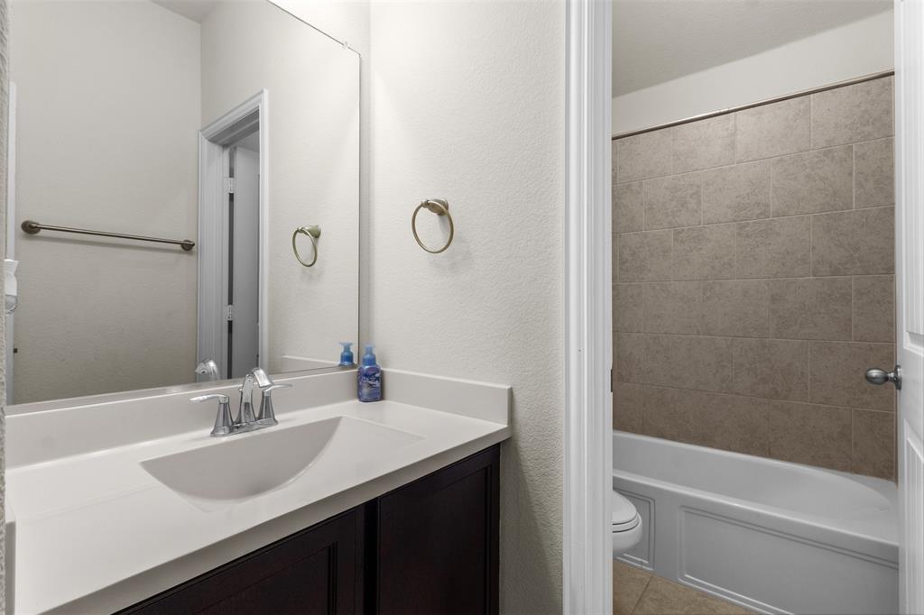1740 Rio Costilla Road Fort Worth, TX 76131 - Photo 31 of 40 Vanity with an integrated sink and countertop, dark wood-finish cabinetry, and a full-width mirror