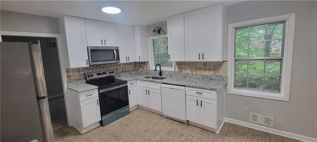 a kitchen with stainless steel appliances granite countertop a stove a sink and a refrigerator