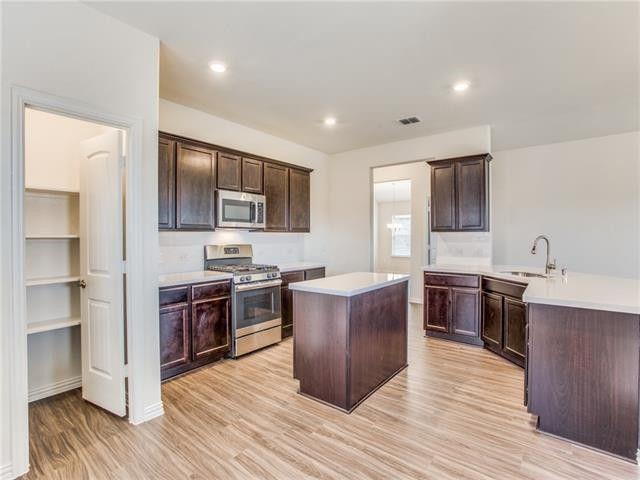 504 Brook View Court Anna, TX 75409 - Photo 6 of 10 a large kitchen with stainless steel appliances granite countertop a stove top oven a refrigerator a sink dishwasher with wooden cabinets and floor