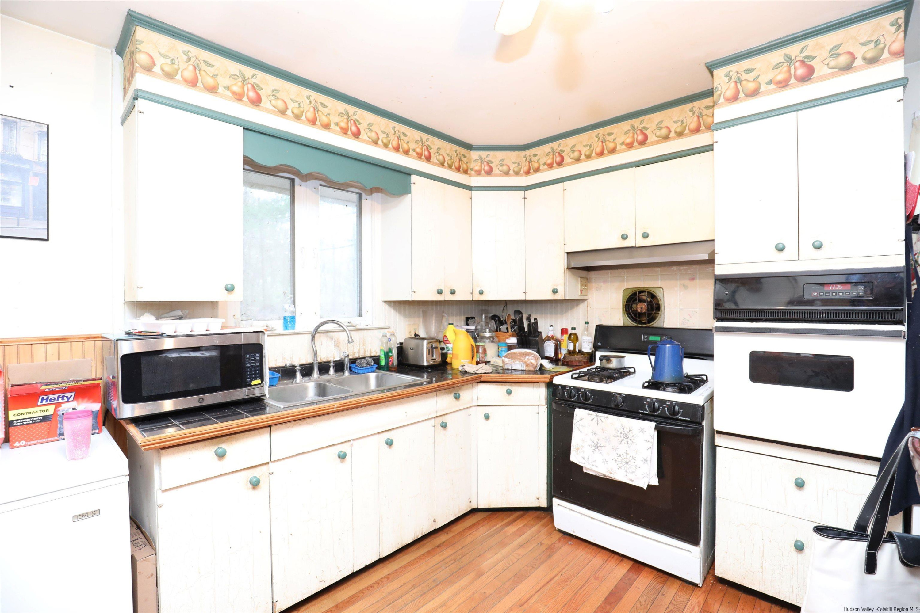 506 Plains Road Wallkill, NY 12589 - Photo 10 of 15 a kitchen with a stove a sink and white cabinets with wooden floor