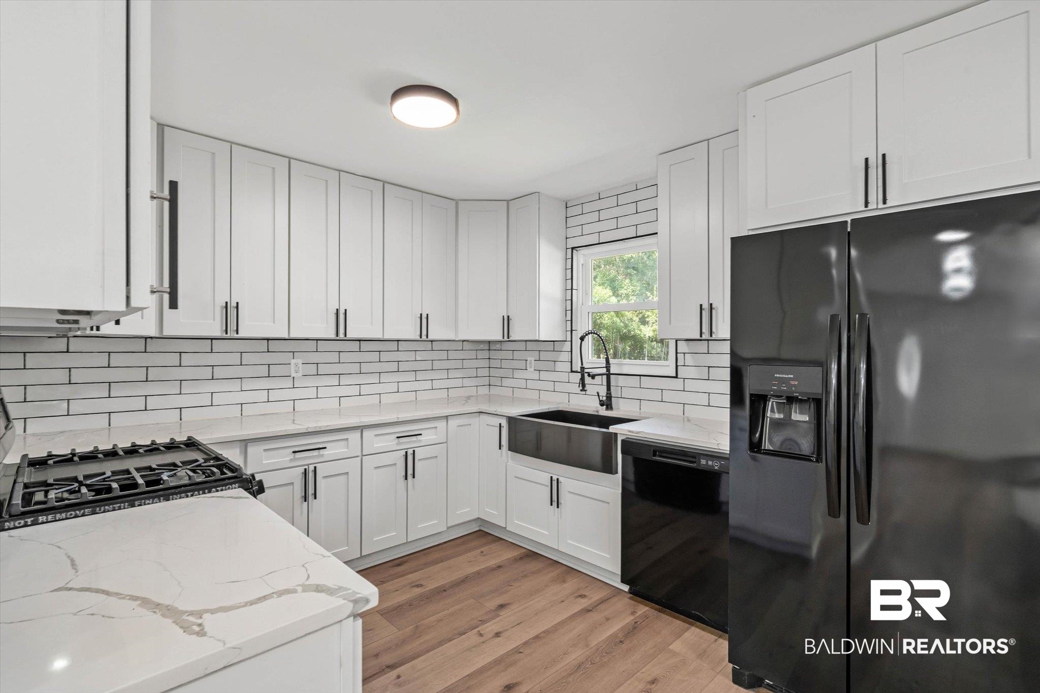 4156 Furman Drive Mobile, AL 36619 - Photo 6 of 24 Kitchen with black appliances, light stone counters, white cabinetry, and light wood-style flooring