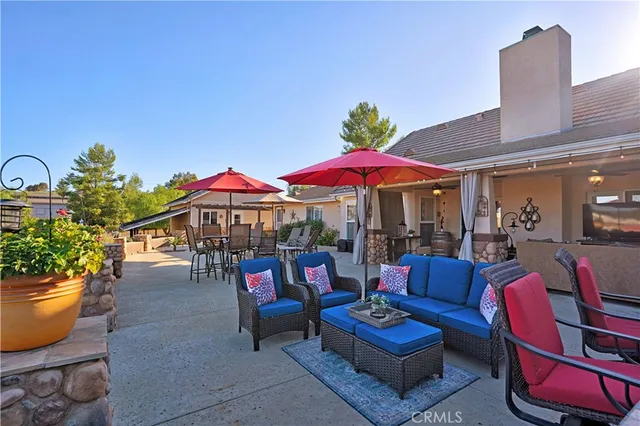 a view of a patio with couches and table and chairs under an umbrella