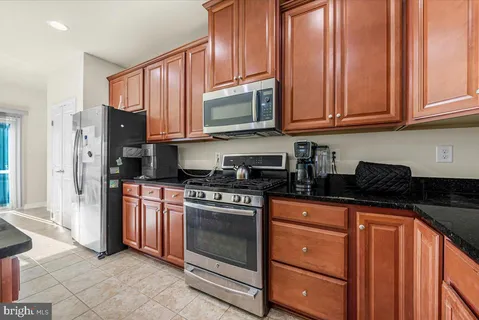 a kitchen with granite countertop stainless steel appliances a stove sink and cabinets