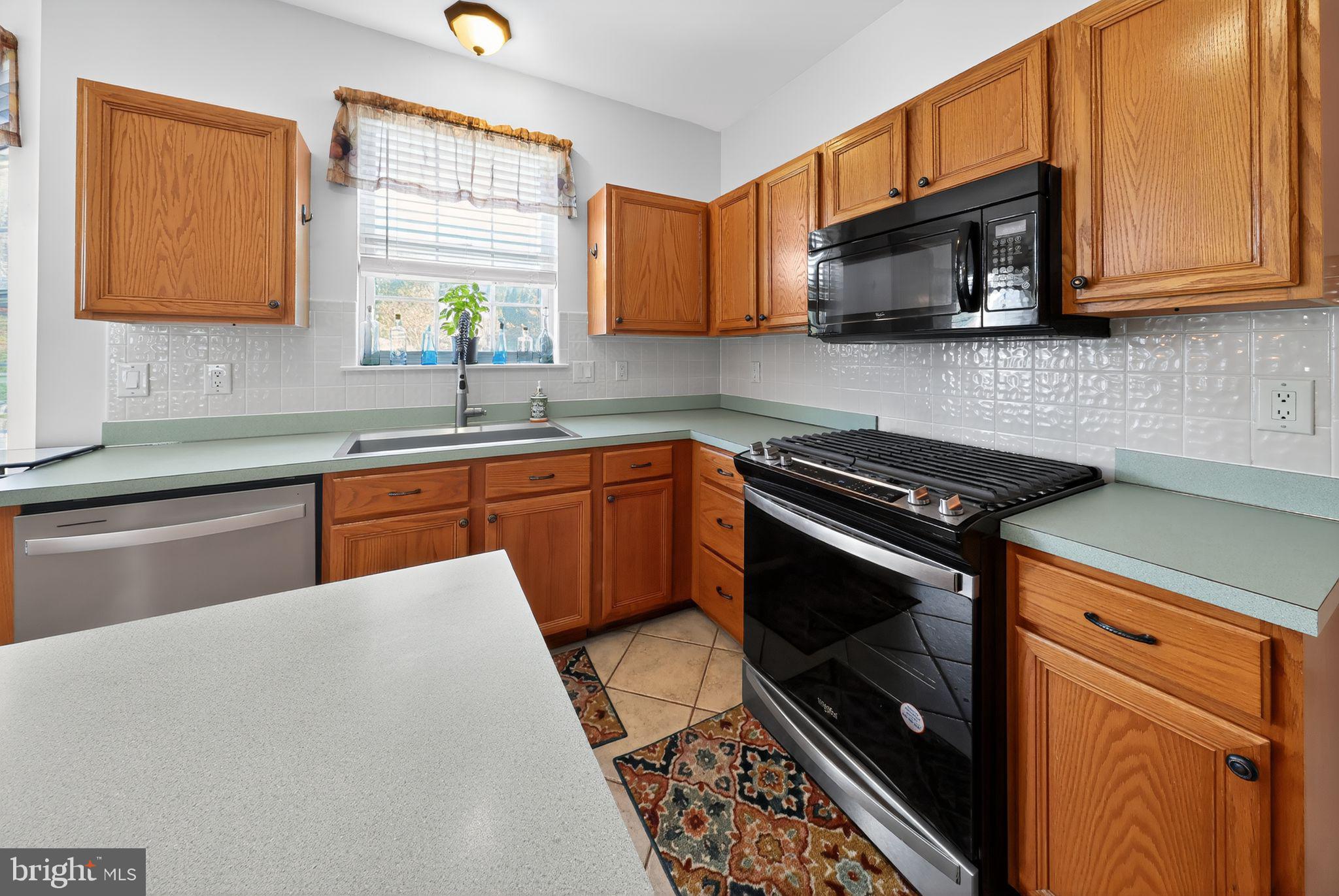 78 Emerald Ridge Drive Bear, DE 19701 - Photo 10 of 30 a kitchen with stainless steel appliances a sink a stove a microwave cabinets and a window