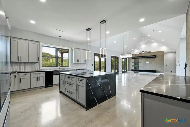 a large kitchen with stainless steel appliances a large counter top a stove and a sink