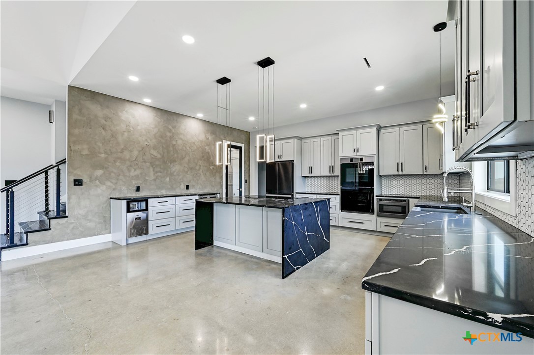 304 Spring Hollow Drive Bertram, TX 78605 - Photo 12 of 45 a kitchen with stainless steel appliances granite countertop a sink counter space cabinets and a large window