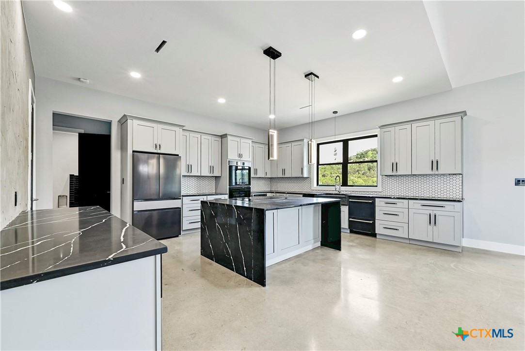 304 Spring Hollow Drive Bertram, TX 78605 - Photo 14 of 45 a large kitchen with stainless steel appliances granite countertop a sink a stove and refrigerator