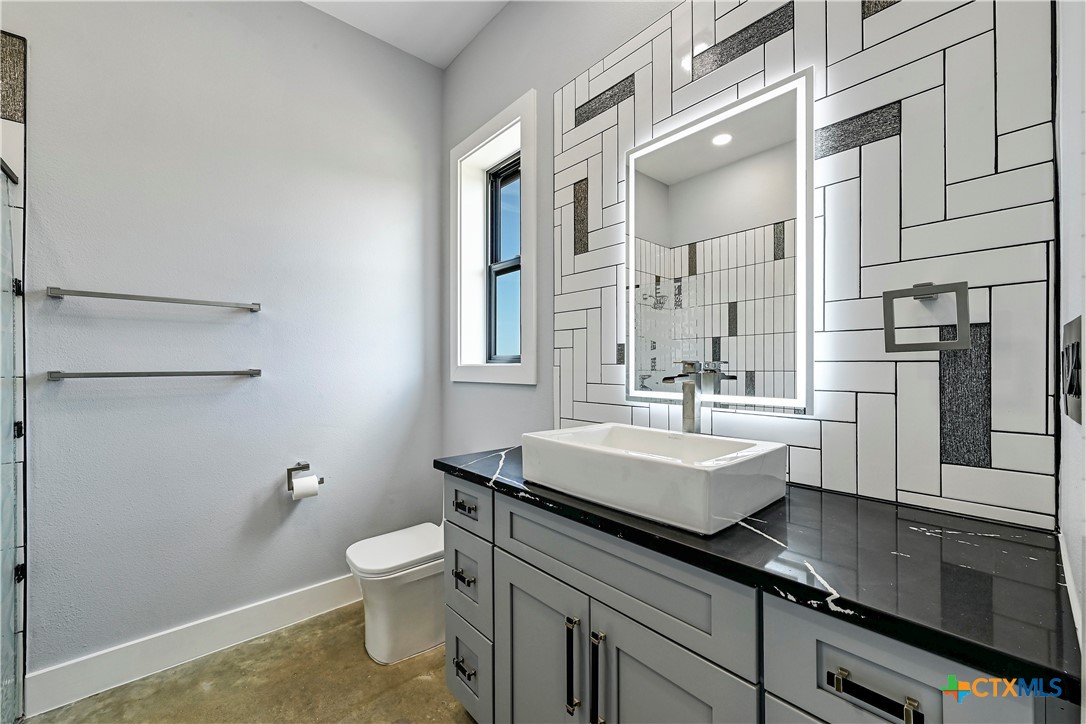 304 Spring Hollow Drive Bertram, TX 78605 - Photo 23 of 45 a bathroom with a sink a toilet a mirror and shower