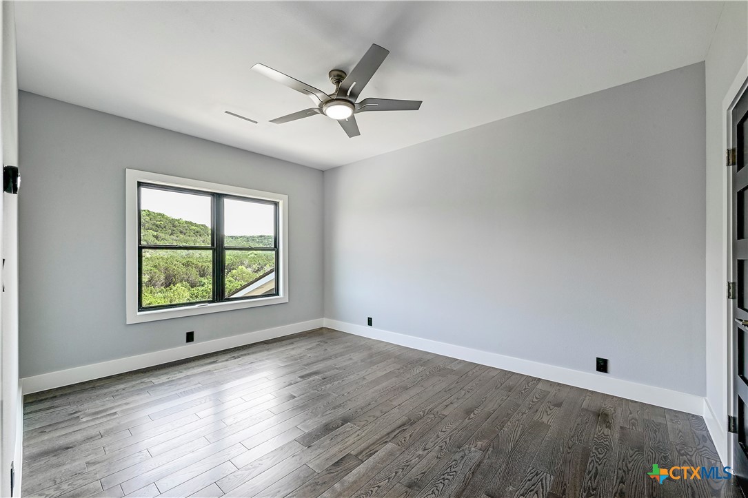 304 Spring Hollow Drive Bertram, TX 78605 - Photo 36 of 45 a view of an empty room with a window and wooden floor
