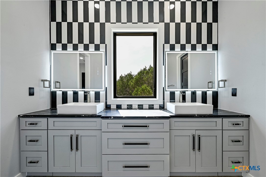 304 Spring Hollow Drive Bertram, TX 78605 - Photo 41 of 45 a bathroom with double cabinets and a mirror