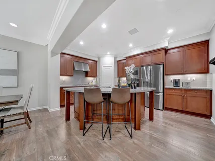 a kitchen with stainless steel appliances kitchen island granite countertop a table chairs sink and cabinets
