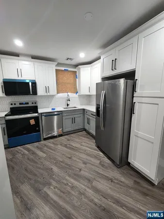 a kitchen with stainless steel appliances granite countertop a refrigerator a stove and a sink