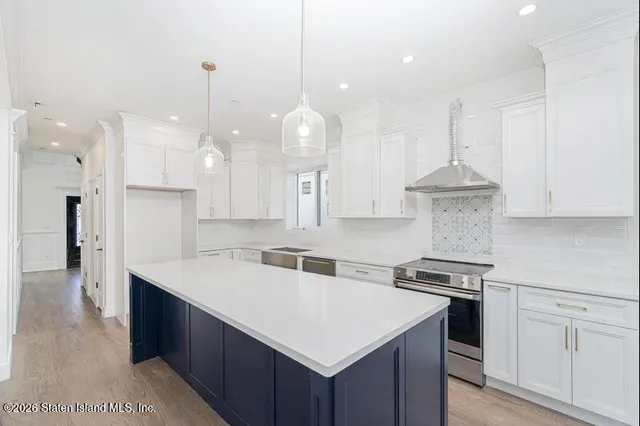 a kitchen with a sink a stove a refrigerator and white cabinets