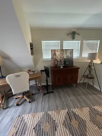 a workspace with wooden floor a book shelf and a window