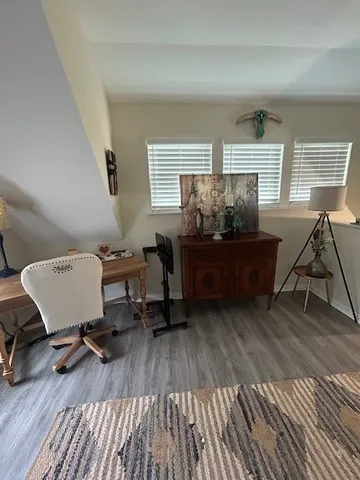a workspace with wooden floor a book shelf and a window