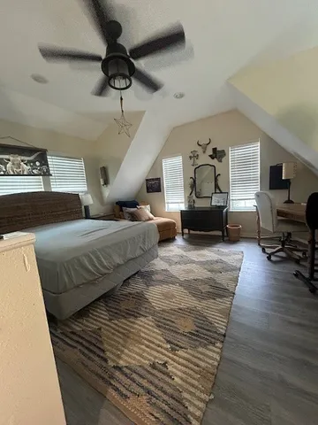 a spacious bedroom with a bed wooden floor and window