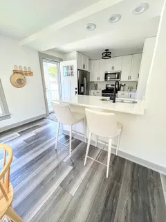 a dining room with kitchen island stainless steel appliances wooden floor and living room view