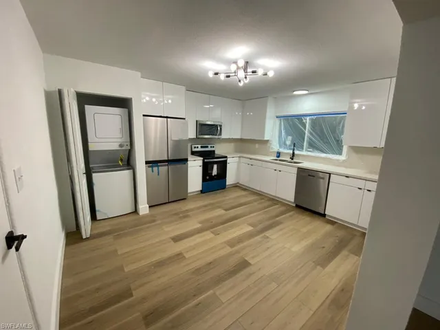 a large kitchen with a refrigerator a sink dishwasher a stove and a refrigerator with wooden floor