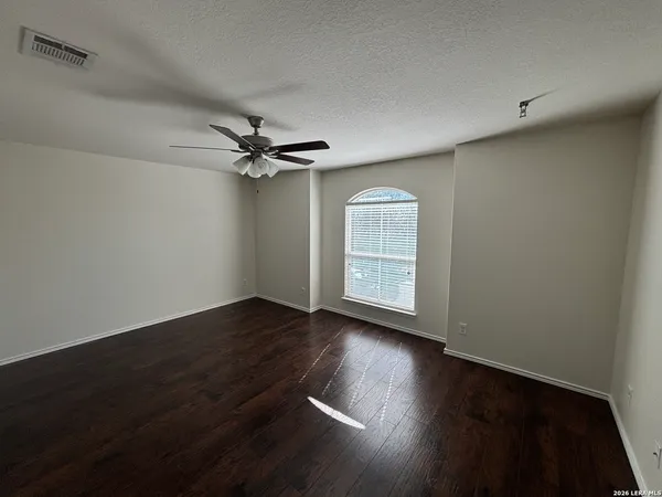 an empty room with wooden floor fan and windows