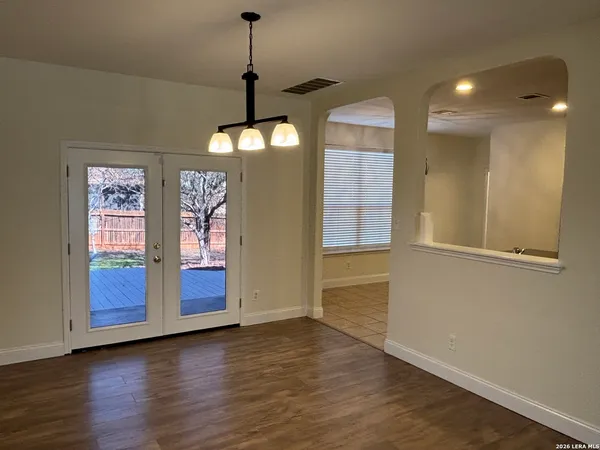 a view of an empty room with window and wooden floor