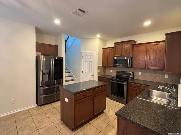 a kitchen with stainless steel appliances granite countertop a refrigerator stove and sink