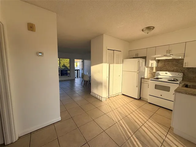 a kitchen with a refrigerator a stove and white cabinets