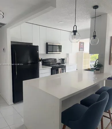 a kitchen with stainless steel appliances a refrigerator a stove a sink and white cabinets