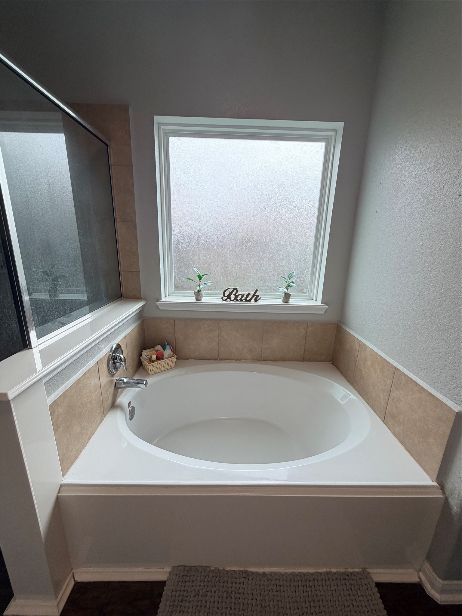 3226 Dappled Vale Trail Spring, TX 77373 - Photo 22 of 26 This bathroom features a cozy corner bathtub with beige tile accents and a frosted window for privacy. A small ledge holds decorative items, adding a touch of charm.