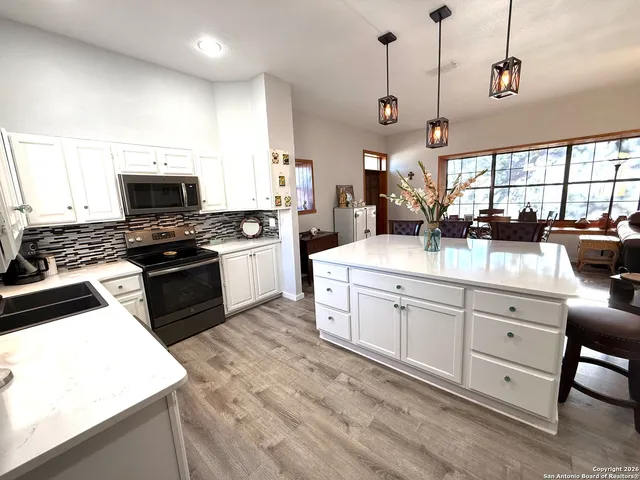 a kitchen with stainless steel appliances kitchen island granite countertop a table chairs and a refrigerator