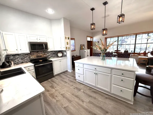 a kitchen with stainless steel appliances kitchen island granite countertop a table chairs and a refrigerator
